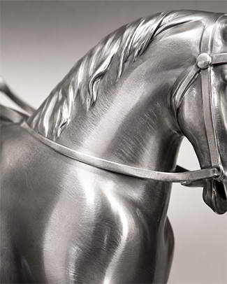 Détail d’une sculpture cheval en inox poli miroir avec une finition argentée brillante.